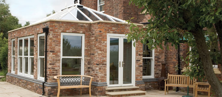 A conservatory with glass roof and brick pillars